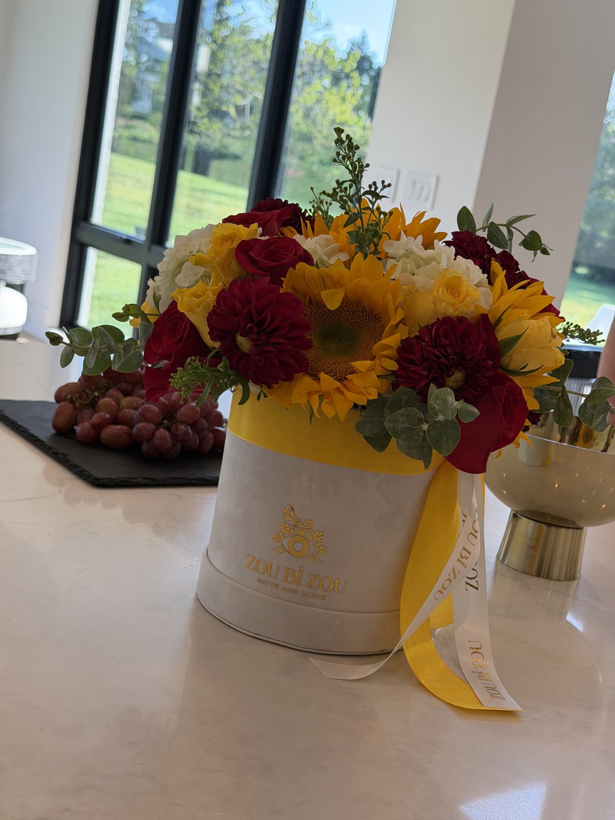 Sunflowers, red dahlias, roses and hydrangea in a white Zou Bi Zou hatbox tied with yellow ribbon